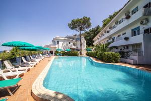a swimming pool with chairs and umbrellas next to a building at Bristol Hotel in Ischia