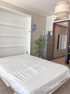 un letto bianco in una camera con frigorifero di La perle du Grau : T1 avec exceptionnelle vue mer a Le Grau-du-Roi