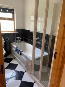 uma banheira na casa de banho com piso preto e branco em Ballyloskey Road em Carndonagh