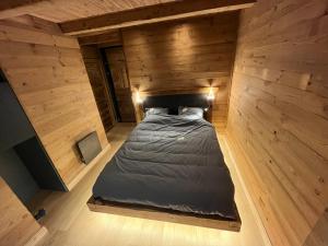 a large bed in a room with wooden walls at L'Ascension - Appartement de standing avec vue "Les Aiguilles" in Valloire