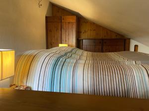 a bed with a striped bedspread in a room at Gli appartamenti della Fra in Torgnon