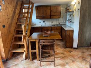 una cucina con tavolo in legno e scala in legno di Gli appartamenti della Fra a Torgnon