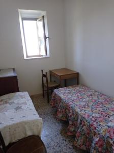 een kamer met 2 bedden, een tafel en een raam bij Casa vacanze Staiti 