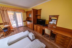 a room with a bed and a desk with a television at Az Idill in Cserszegtomaj