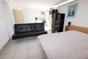 a bedroom with a black leather couch in a room at LE STUDIO SELESTADIEN in Sélestat