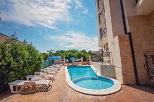 a swimming pool with lounge chairs next to a building at Hotel Santa Maria in Obzor