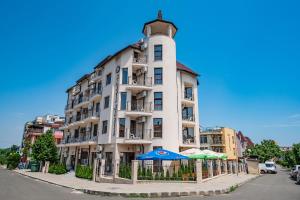 a tall white building with umbrellas in front of it at Hotel Santa Maria in Obzor