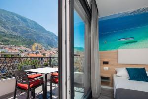 a bedroom with a balcony with a bed and a table at Villa Loriana Apartments in Makarska