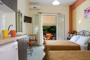 a hotel room with two beds and a kitchen with a balcony at Natasa Studios in Mikros Gialos