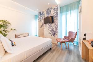 a bedroom with a bed and a chair and a tv at Hotel Majorca in Gabicce Mare