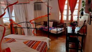 a bedroom with two beds and a chair and windows at Chez Coumbis in Gorée