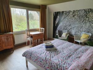 een slaapkamer met een bed en een tafel en stoelen bij Villa Kakelbont Borgloon in Borgloon