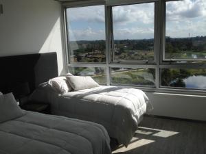 a bedroom with two beds and a large window at Faros de Carrasco Apartments in Montevideo +21 photos