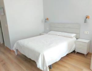 トレモリノスにあるLa Nogaleraの白いベッドルーム(ベッド1台、ナイトスタンド付)