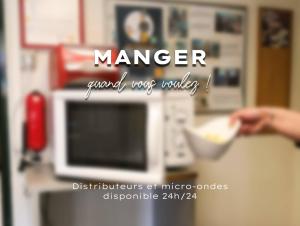 a person holding a bowl of food in front of a microwave at Premiere Classe Rodez in Rodez