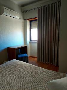 a bedroom with a bed and a window and a desk at Hotel Nova Cidade in Amadora