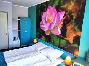 ウストカにあるPod Różą B&Bのベッドルーム1室(壁にピンクの花の大きな絵画付)