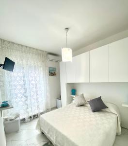 a white bedroom with a bed and a window at Casa Tortora in Santa Maria di Castellabate