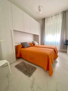 a bedroom with two beds with orange sheets and a rug at Casa Tortora in Santa Maria di Castellabate
