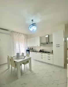 a kitchen with a white table and chairs and a table and a kitchen at Casa Tortora in Santa Maria di Castellabate