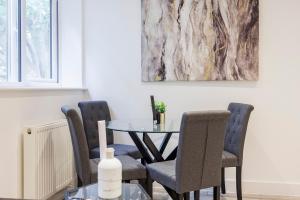 濱海紹森德的住宿－Modern apartment -Perfect for Contractors & Families By Luxiety Stays Serviced Accommodation Southend on Sea，一间带桌椅和绘画的用餐室