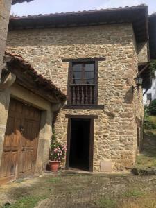 a stone building with a door and a balcony at La Casita in Cabezón de Liébana