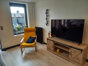 フェカンにあるGîte 8 places à Fécamp La Bonne Escaleのリビングルーム(テレビ、黄色い椅子付)