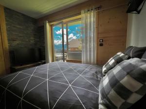 a bedroom with a large bed and a large window at Alt 985M - Appartement de Charme au Grand-Bornand in Le Grand-Bornand