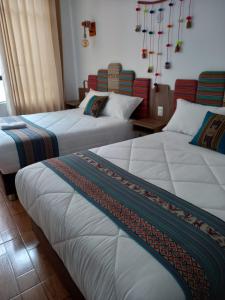 two beds in a hotel room with chandeliers at Yanay Collection in Machu Picchu