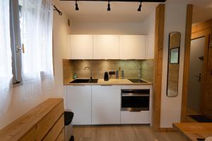 a kitchen with white cabinets and a sink and a window at Alt 985M - Appartement de Charme au Grand-Bornand in Le Grand-Bornand