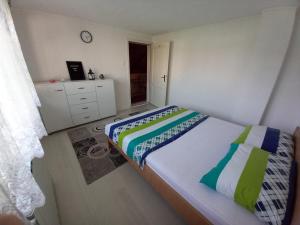 a bedroom with a bed and a dresser with a clock at Apartment Maida in Dubrave Gornje