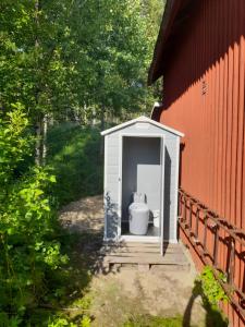 a toilet in a shed next to a red building at Small bedroom, outside toilet, shower kitchen, 120 m from Sandbach in Bräcke
