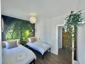 two beds in a room with a painting on the wall at Coastline Retreats - Stunning Balcony Apartment with Sea Views - Alice in Wonderland Themed Secret Room - Luxury Copper Bath in Master Bedroom in Southbourne