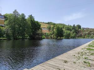 a river with a wooden walkway next to the water at Casa Penedo do Raposo in Muxagata