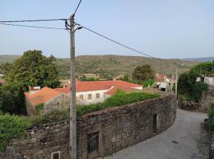 a stone wall next to a street with houses at Casa Penedo do Raposo in Muxagata