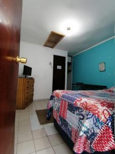 a bedroom with a bed and a blue wall at Hostal Caleta Abarca in Viña del Mar
