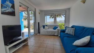 een woonkamer met een blauwe bank en een televisie bij Villa Selene in Archangelos