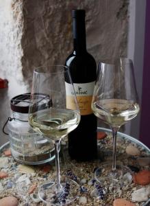 two glasses of white wine next to a bottle of wine at Apartment Roby in Vrsar +7 photos