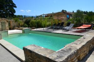 a swimming pool with a stone wall around it at LES JARDINS DU VENTOUX in Crillon-le-Brave