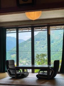 a room with a table and chairs in front of a window at 古民家ステイMatoba in Miyoshi