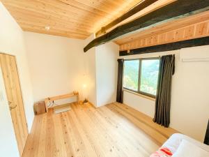 an empty room with a bed and a window at 古民家ステイMatoba in Miyoshi