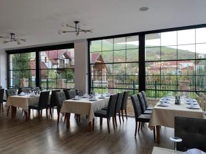 a dining room with tables and chairs and large windows at Grand Hotel Pogradec in Pogradec