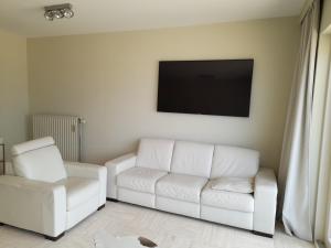a living room with a white couch and a tv at Kristof701 in De Panne