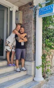 a woman hugging a man on the steps of a house at Ephesian Hotel & Guesthouse in Kusadası
