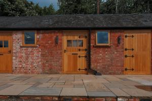 a brick building with wooden doors and windows at Eakley Stables 2 - Pogo in Newport Pagnell