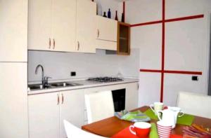 cocina con armarios blancos y mesa de madera en Home NIKY LAKE, en Desenzano del Garda