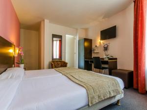 ein Hotelzimmer mit großem Bett und Schreibtisch in der Unterkunft Hotel Arc Paris Porte d'Orléans in Montrouge