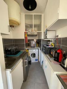 uma pequena cozinha com armários brancos e uma máquina de lavar roupa em LE PROVENCAL - Hyper centre - Clim - Terrasse em Cassis