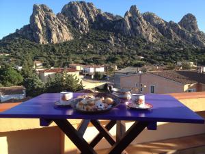 a table with a plate of food on a balcony with mountains at Antica Dimora La Corona in San Pantaleo