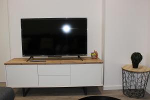 een tv op een witte kast in een woonkamer bij L'instant T 4* Balnéo, Sauna et Parking Privé in Colmar